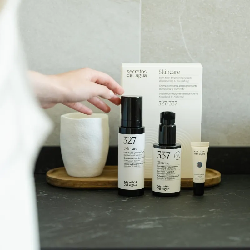 Productos faciales Secretos del Agua junto a una taza blanca.